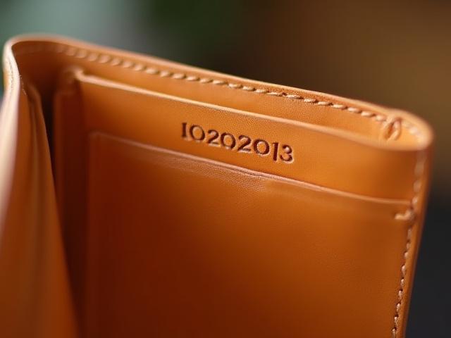 A small date '10.22.2023' stamped on the interior of a tan leather wallet